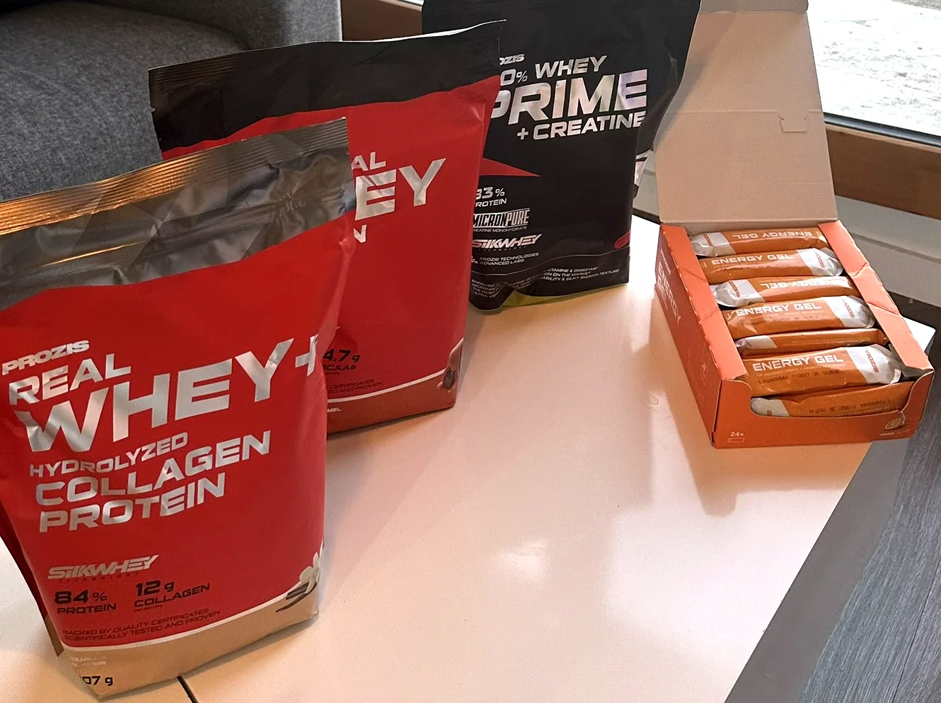 Les quatre produits Prozis reçus : deux sachets rouges, un sachet noir et une boîte d’Energy Gel ouverte